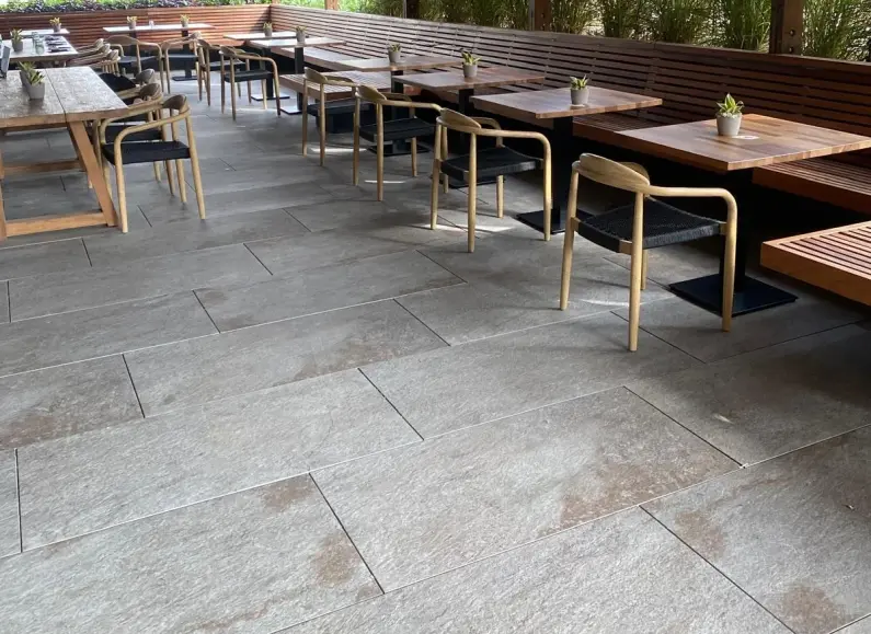 Restaurant terrace with wooden tables on grey flooring