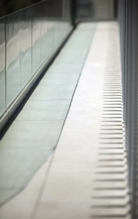 Outdoor walkway with light flooring beside a glass railing