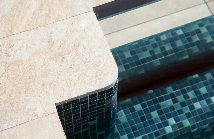 Pool edge with stone flooring and green mosaic tiles